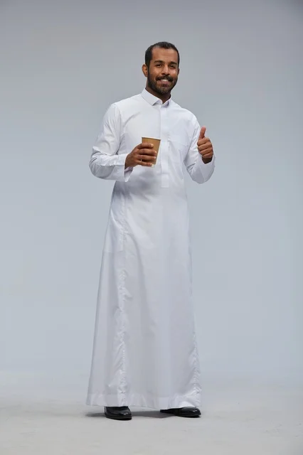 Smiling Saudi man holding a coffee cup in traditional attire
