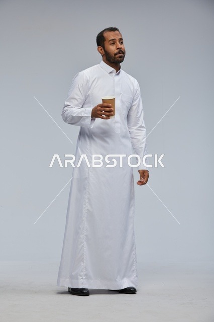رجل سعودي بالثوب التقليدي يحمل كوب قهوة