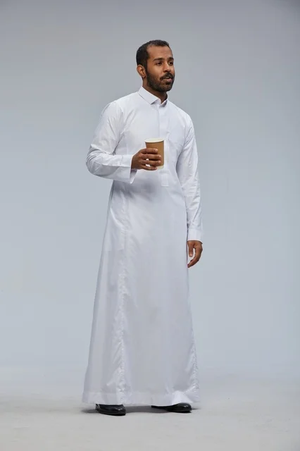 رجل سعودي بالثوب الأبيض يحمل كوب قهوة في الاستوديو