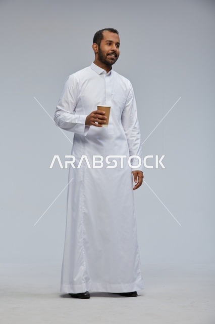 رجل سعودي بالثوب التقليدي يحمل كوب قهوة