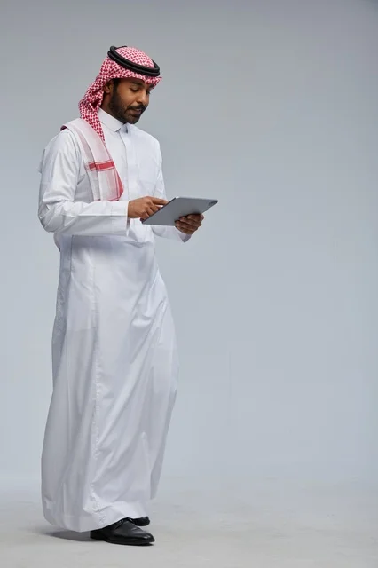 رجل سعودي بالزي التقليدي يستخدم جهاز لوحي