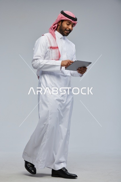 Saudi man using tablet in traditional attire