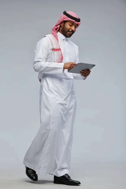 Saudi man using tablet in traditional attire