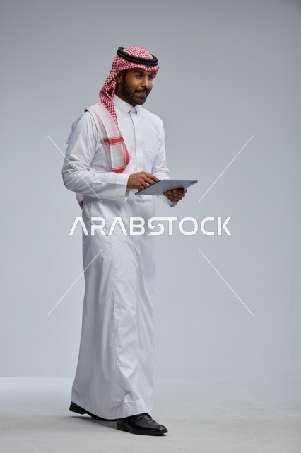Saudi man using tablet in traditional attire