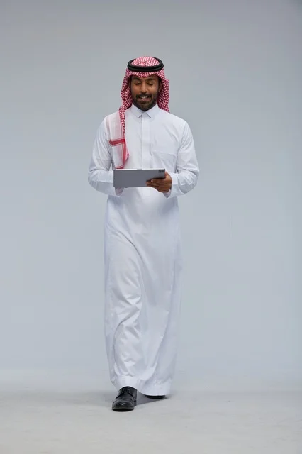 Saudi Man Using Tablet in Traditional Thobe Walking