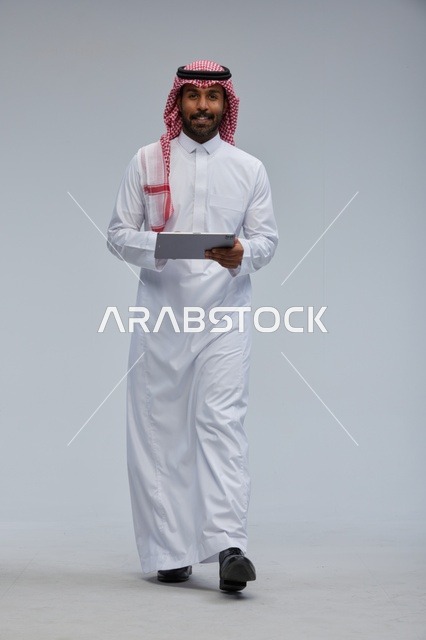 Saudi man using tablet in traditional attire