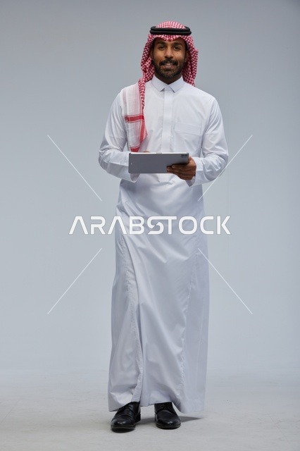 Saudi man using tablet in traditional attire