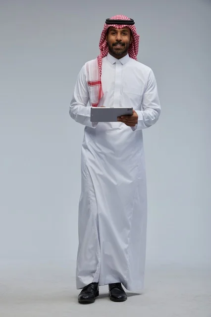 Saudi man using tablet in traditional attire