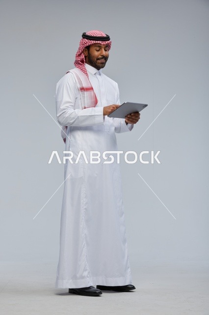 Saudi man using tablet in traditional attire