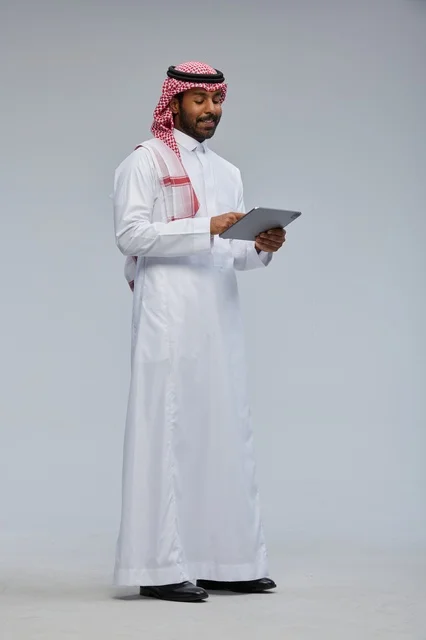 Saudi man using tablet in traditional attire
