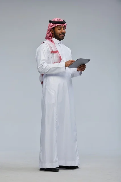 Saudi man using tablet in traditional attire