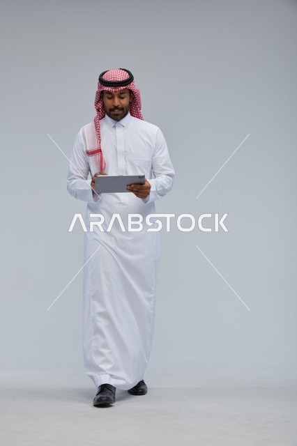 Saudi man using tablet in traditional attire