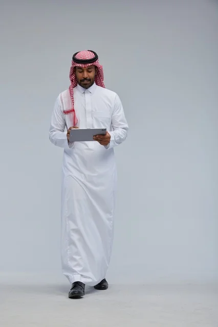 Saudi man using tablet in traditional attire