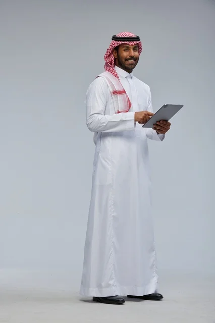 Saudi Man in Traditional Thobe Using Digital Tablet