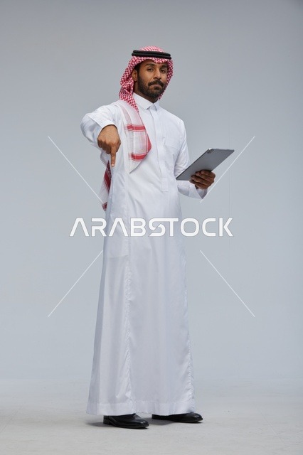 Saudi man using tablet in traditional attire
