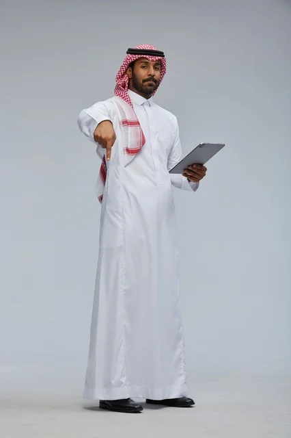 Saudi man using tablet in traditional attire