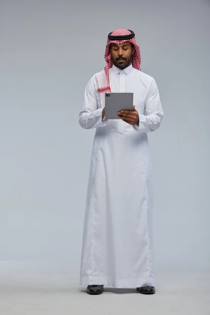 Saudi Man in Traditional Thobe Using Tablet