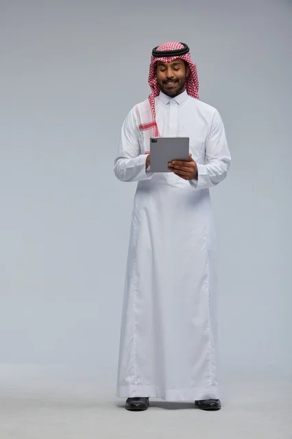 Saudi Man in Traditional Thobe Using a Digital Tablet