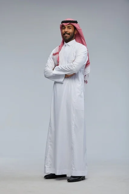رجل سعودي مبتسم بالزي التقليدي وذراعاه متقاطعتان رجل سعودي مبتسم بالزي التقليدي وذراعاه متقاطعتان