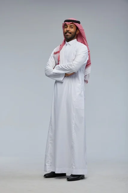 رجل سعودي بالزي التقليدي يقف بذراعين متقاطعتين