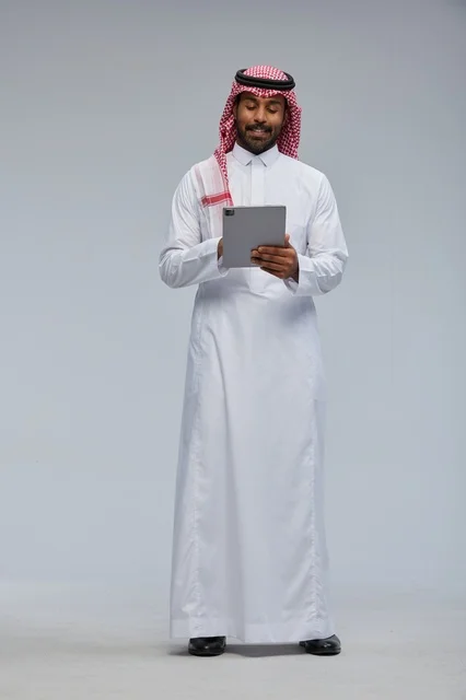 رجل سعودي يستخدم جهاز لوحي رقمي بالزي السعودي التقليدي