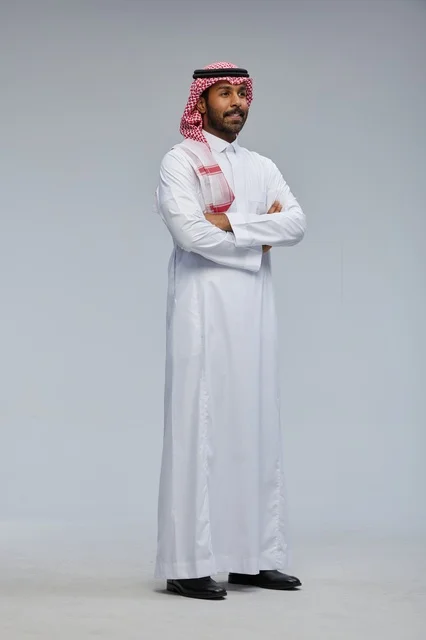رجل سعودي مبتسم بالزي التقليدي وصورة شخصية كاملة بالاستوديو