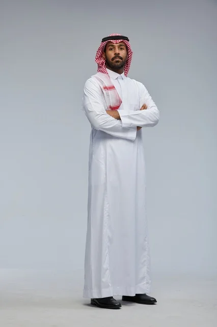رجل سعودي بالزي التقليدي يقف بذراعين متقاطعتين