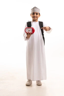 Omani Schoolboy Holding Red Alarm Clock with Backpack