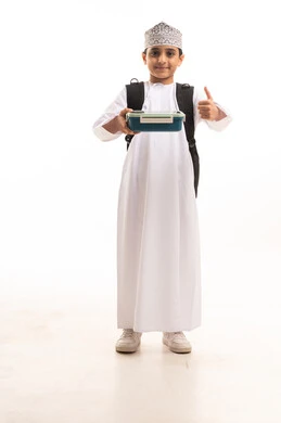 طالب مدرسي عماني يحمل علبة غداء وحقيبة