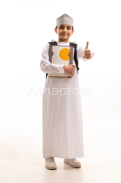 طالب عماني بالزي التقليدي والكمة يحمل كتباً