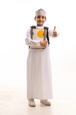 طالب عماني بالزي التقليدي والكمة يحمل كتباً
