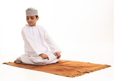Omani Boy in Traditional Dress Praying on Mat