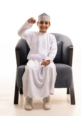 Smiling Omani Boy in Traditional Dress with Victory Gesture