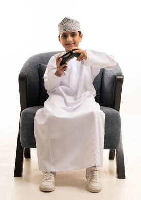 Omani Boy in Traditional Dress Playing Video Games