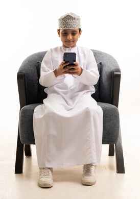 Omani Boy Using Smartphone in Traditional Dress