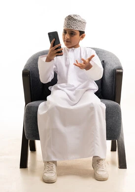 Omani Boy in Traditional Dress Using Smartphone
