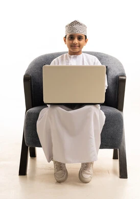 Omani Boy Using Laptop in Traditional Dress