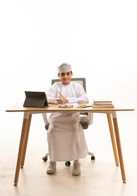 Omani Student Studying at Wooden Desk with Digital Tablet