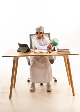 Omani Boy Studying at Desk with Globe