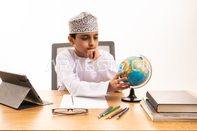 طفل عماني يدرس مع مجسم الكرة الأرضية