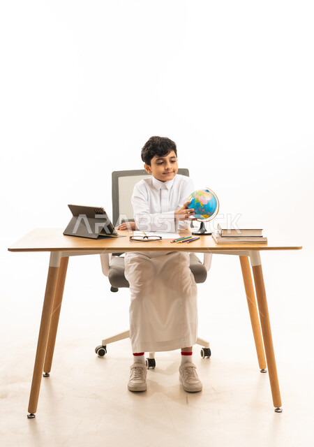 Saudi Schoolboy Studying with Globe and Tablet at Desk