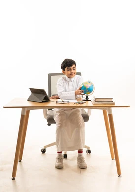 Saudi Schoolboy Studying with Globe and Tablet at Desk