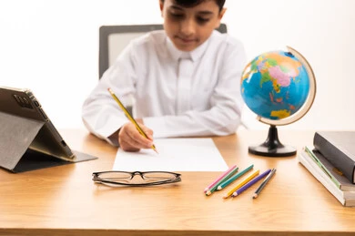 Saudi Boy in Traditional Thobe Studying at Desk