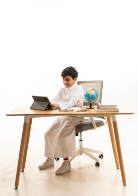 Saudi Boy Using Tablet for Learning at Desk