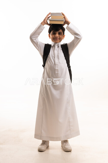 طالب سعودي بالثوب الأبيض يحمل كتباً فوق رأسه