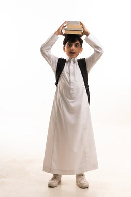 طالب سعودي بالثوب التقليدي مع كتب مدرسية خلفية بيضاء
