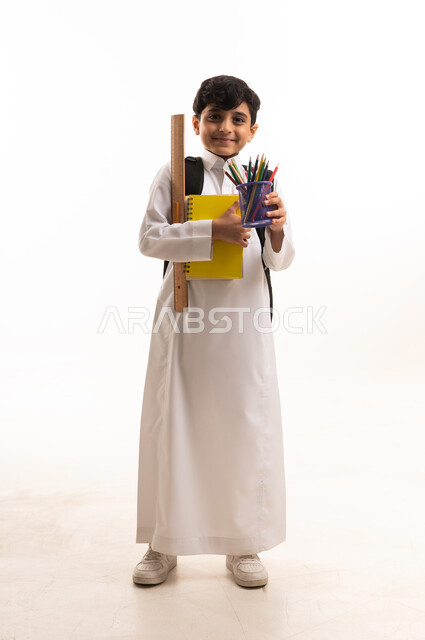 طالب سعودي بالثوب التقليدي مع أدوات مدرسية