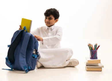 طالب سعودي بالثوب مع حقيبة وأدوات مدرسية
