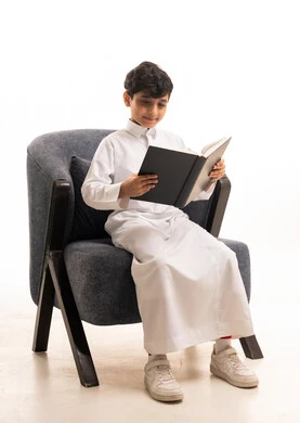 Saudi Boy in Traditional Thobe Reading Book