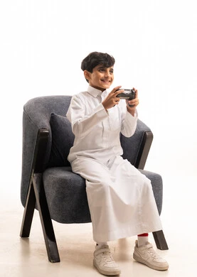 Saudi Boy in White Thobe Playing Video Games